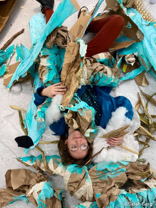 Artist lying on floor amidst pieces of giant sculpture
