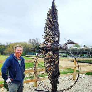 John Pahlas beside his giant, steel Heron scupture at K&A Greenhouse